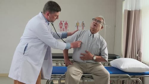 Doctor health checks elderly patient in bed of emergency room at hospital ward.