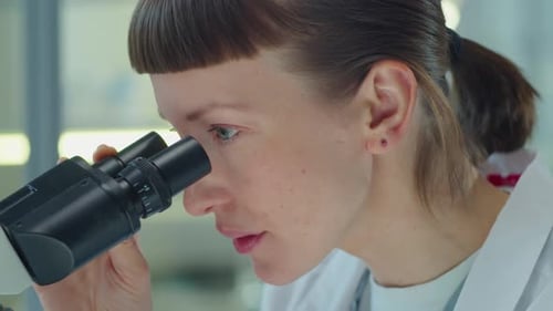 Woman Scientist Looking Through Microscope in Laboratory