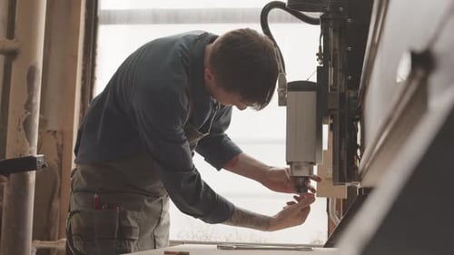 Carpenter Repairing CNC Machine in Workshop
