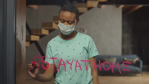 Woman Writes Stay At Home on Glass Door