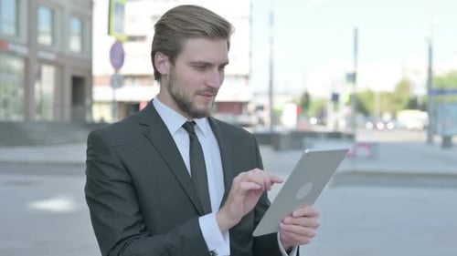 Excited Businessman Using Tablet on City Street