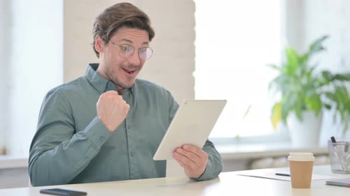Excited Man Celebrates Success on Tablet