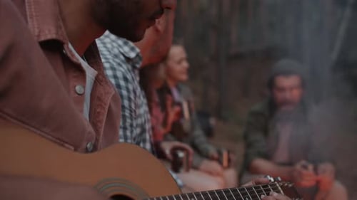 Friends Enjoying Campfire Music in Forest at Night