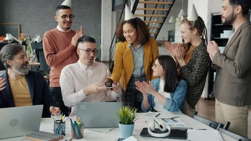 Employees Congratulating Man on Birthday Giving Cake in Office While Guy Blowing Candle Making Wish