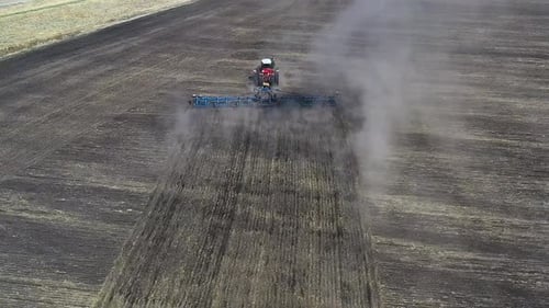 Red Tractor Cultivating Brown Earth in Sunny Spring Autumn Weather