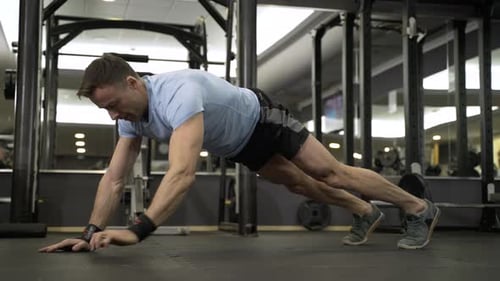 Muscular man practicing elbow plank exercise at the gym.