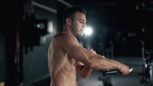 A Muscular Sportsman is Doing Exercise in the Gym