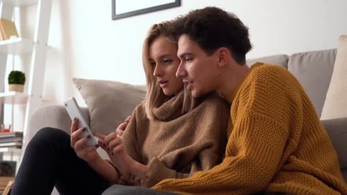 Happy Couple Using Smartphone Together Indoors
