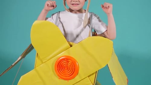 Fröhliches Kind im Flugzeug aus Pappe