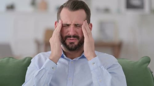 Man Experiencing Headache, Rubbing Temples in Home