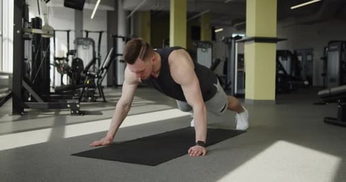 Young Muscular Athlete Works Out in a Modern Gym Making Push Ups Exercises