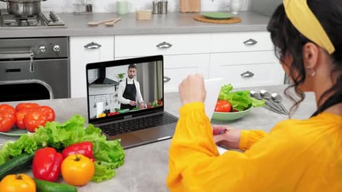 Lección de cocina en línea para mujeres en la cocina, escucha, el chef escribe en un cuaderno