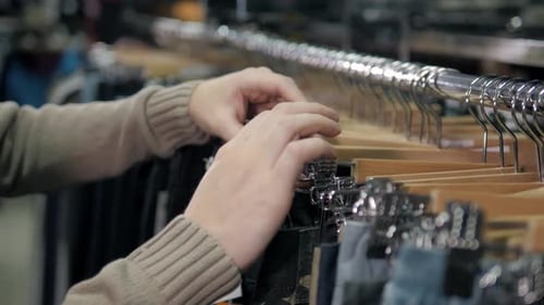 Hands Browse Jeans on Rack in Clothing Store