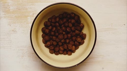 Chocolate Cereal Being Poured in Bowl with Milk
