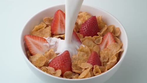 Milk Pouring into Bowl of Cereal and Strawberries