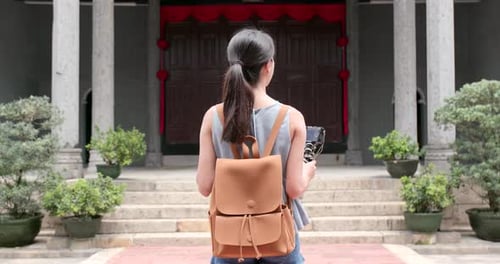 Woman holding camera to take video and walk into chinese temple