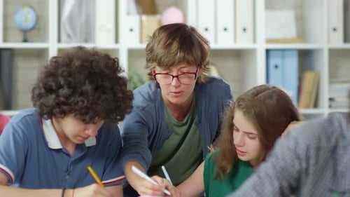Teacher Helping Students With Schoolwork in Classroom