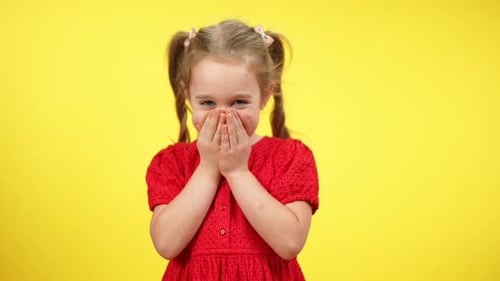 Petite fille timide et mignonne riant en fermant la bouche avec les mains