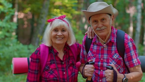 Smiling Senior Couple Hiking Through Forest