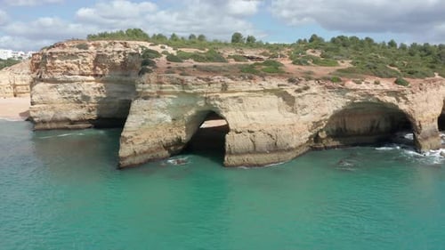 Aerial of cave on shoreline near a beautiful blue sea