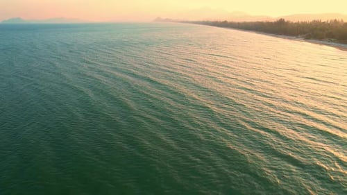 Vista aérea de 4K do drone se movendo no belo mar. pôr do sol sobre ondas do mar e praia de areia.