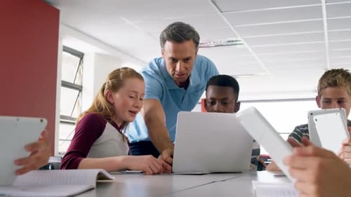 Profesor que ayuda a los escolares en una computadora portátil 4k