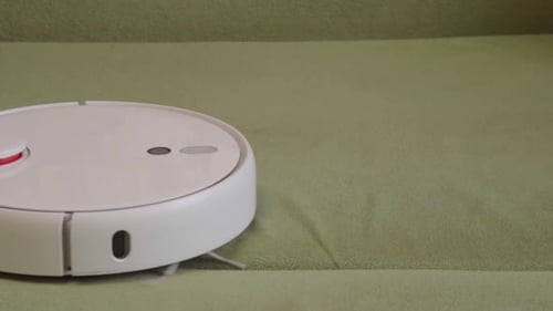 Robot Vacuum Cleaner Cleaning Green Couch