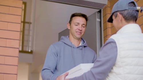 Cheerful Courier in Cap Delivering Pizza to Man at His Home