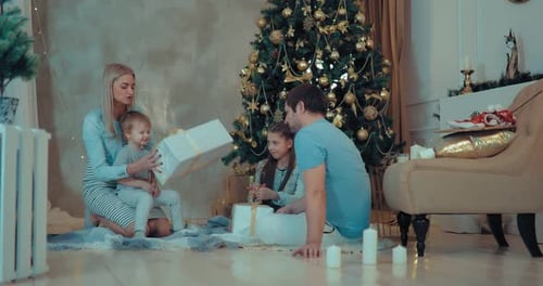 Family Opens Christmas Presents near Decorated Tree