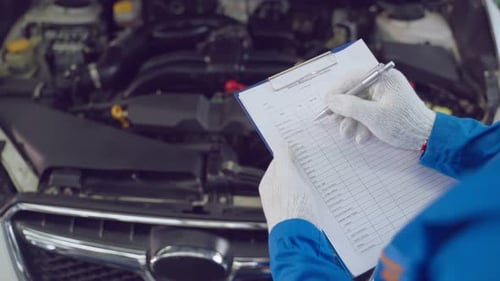 Asiatischer Kfz-Mechaniker hält Checkliste Zwischenablage überprüfen Motor.