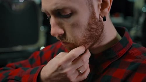 Young Man with Beard Touches His Face
