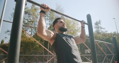 Young and Muscular Man Doing Pullups on Horizontal Bar During His Workout