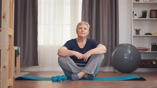 Woman Sitting on Exercise Mat at Home