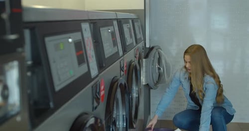 Woman Loads Laundry at Bright Laundromat