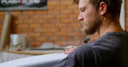 Man examining a surfboard 4k