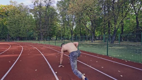 Shirtless Man Sprinting on Running Track Outdoors