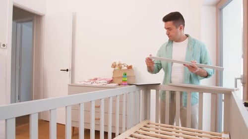 Father with Tablet Pc Assembling Baby Bed at Home 15