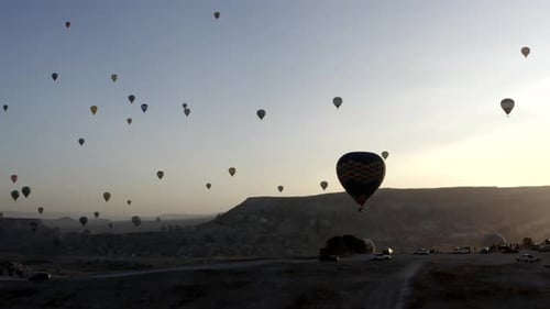 Balloons Soar Over Rocky Landscape at Sunrise