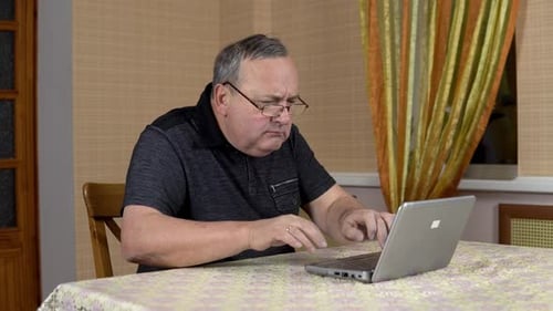 Mature Adult Typing on Laptop in Home Interior
