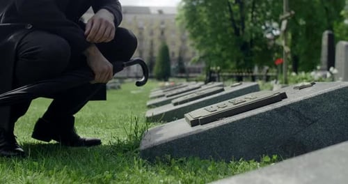 Trauriger junger Mann im Anzug steht auf dem Grab des Stadtfriedhofs