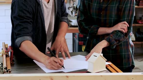 Close up of Carpenter and architect are planning construction of built-in furniture in wood workshop