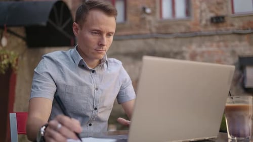 Smiling Man with Works From Home in His Kitchen Using a Laptop