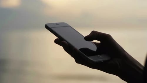 Silhouette of Woman Texting on Phone at Sunset