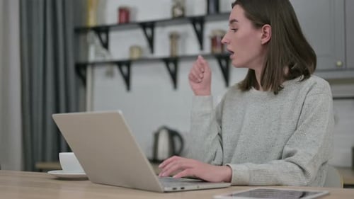 Woman Coughing While Using a Laptop at Home
