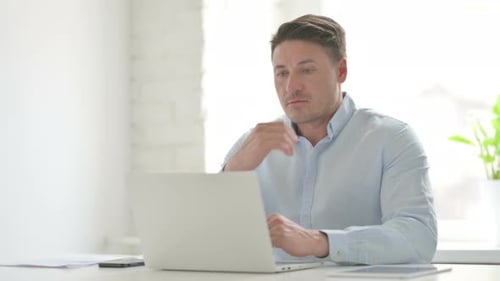 Man Thinking while Working on Laptop in Office
