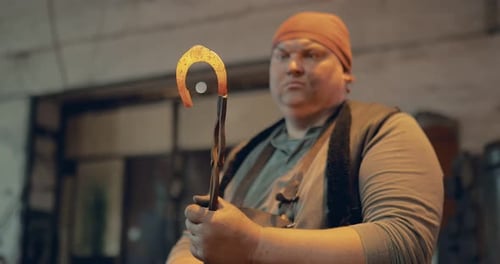 Blacksmith Man Holding Red-Hot Metal with Tongs