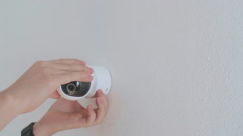 Hands Installing Modern Security Camera on Wall
