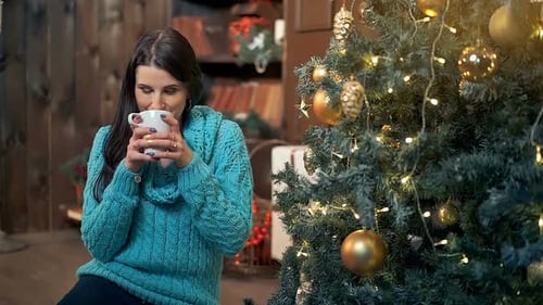 Woman Drinking Tea Beside Christmas Tree