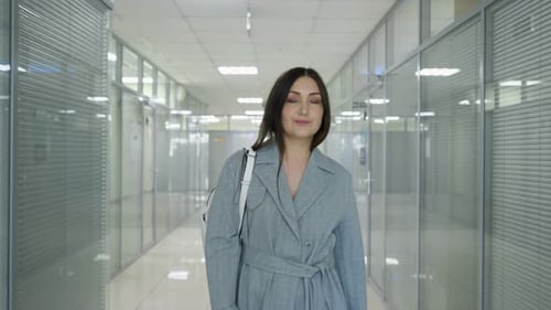 Young Woman with Loose Hair Walks Along Hall with Offices