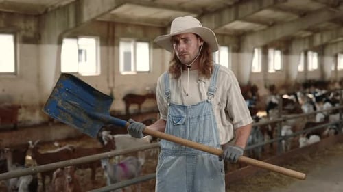 Farmer With Shovel Standing In Goat Barn